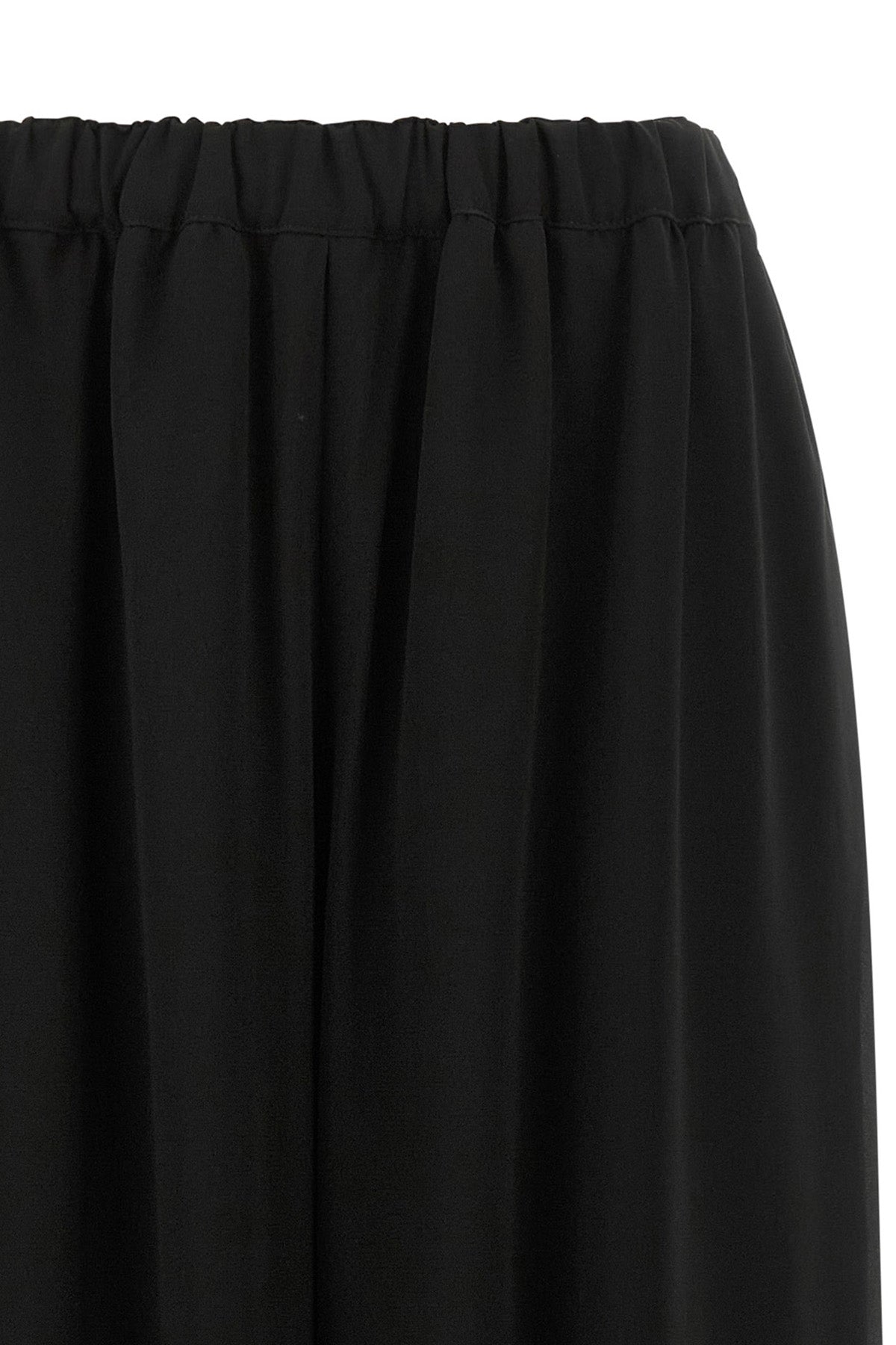 the comme des garcons trousers are distinguished by a fluid and voluminous silho