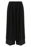 the comme des garcons trousers are distinguished by a fluid and voluminous silho